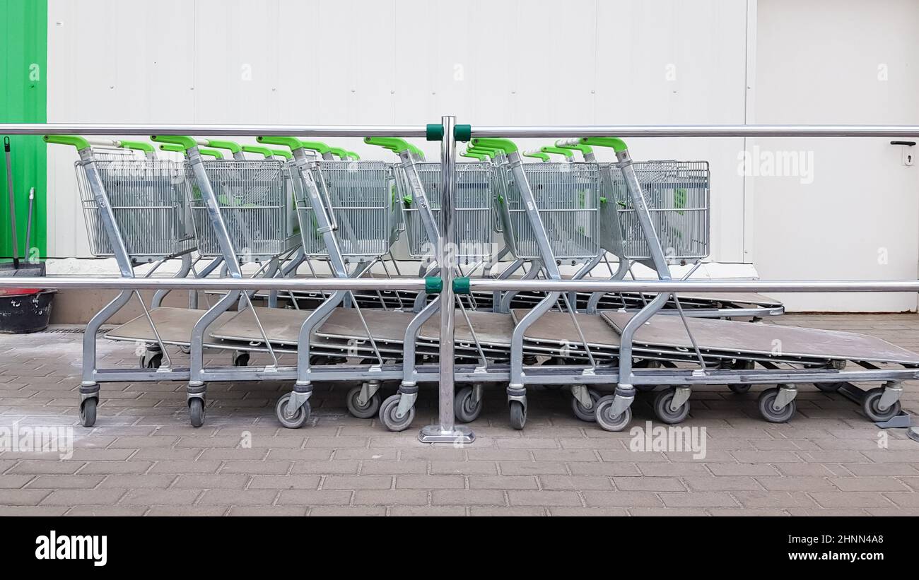 Molti carrelli in metallo sono parcheggiati in fila vicino a un supermercato all'aperto. Concetto di trading. Foto Stock