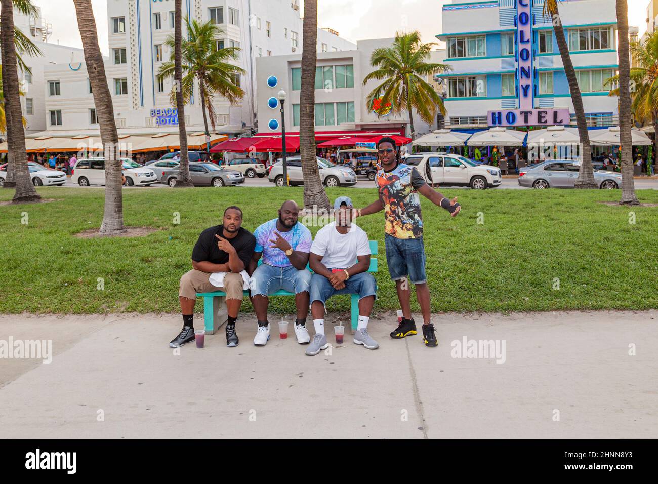 persone nere che posano e si siedono su una panchina all'ocean drive con colony hotel in background Foto Stock