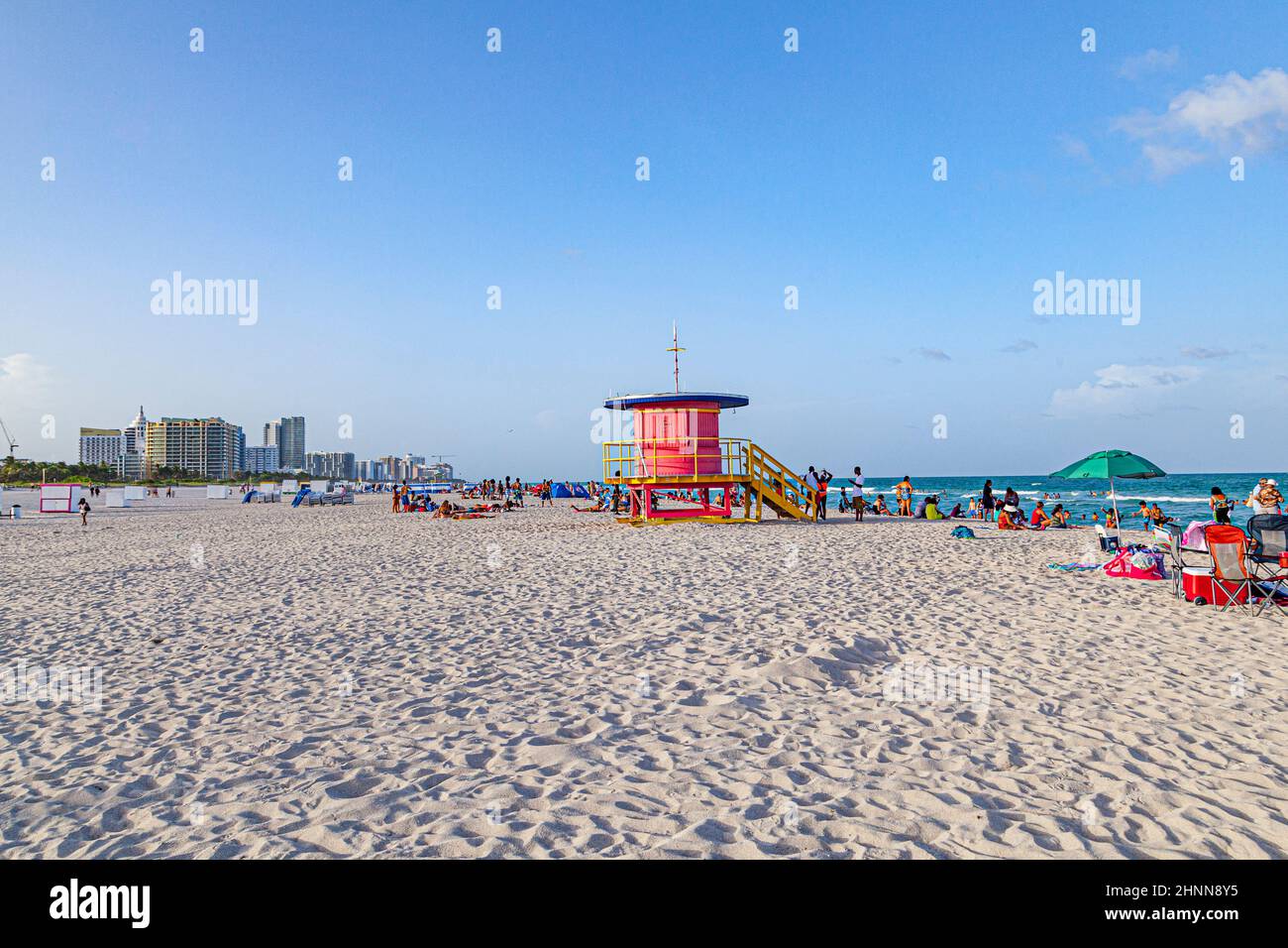 La gente gode della spiaggia sud a Miami Beach e si siede di fronte alle colorate torri di bagnino Foto Stock