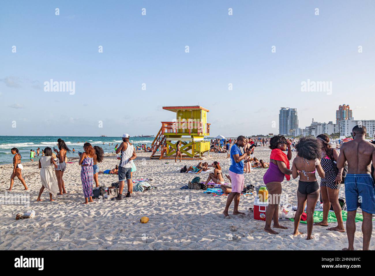La gente gode della spiaggia sud a Miami Beach e si siede di fronte alla colorata torre del bagnino Foto Stock