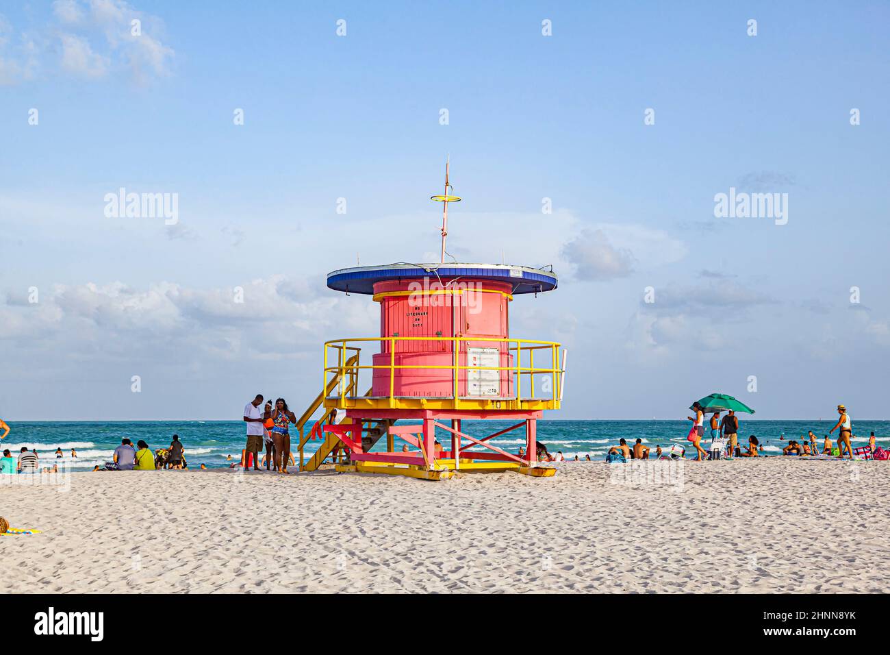 La gente gode della spiaggia sud a Miami Beach e si siede di fronte alla colorata torre del bagnino Foto Stock