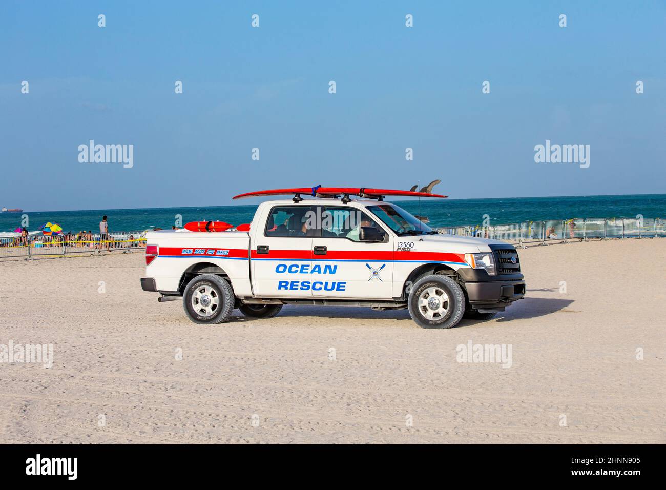 La gente gode di South Beach a Miami Beach e dei controlli dell'auto di salvataggio dell'oceano per la sicurezza con una tavola da surf sulla parte superiore Foto Stock