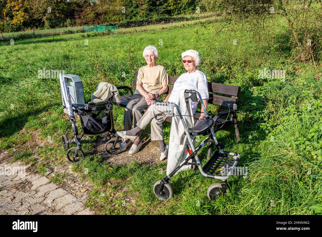 la coppia femminile anziana gode del sole primaverile mentre si siede su una panca Foto Stock