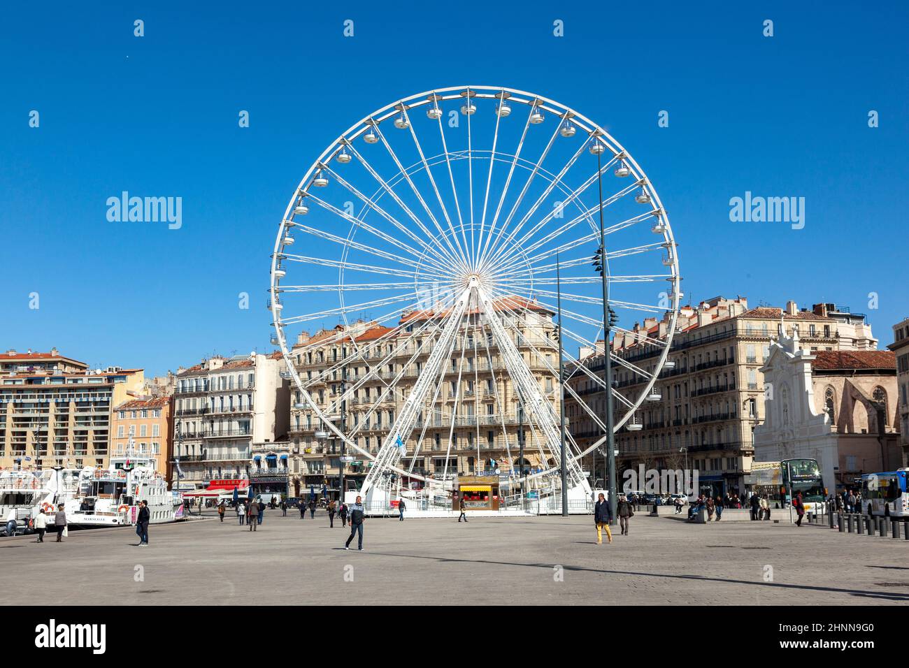 La gente gode di una grande ruota di ferro contro un cielo blu a Marsiglia Foto Stock