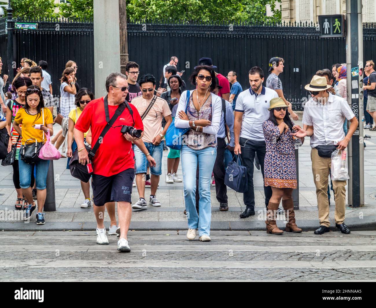 La gente attraversa la strada ad una luce fraffica per i pedoni ad un incrocio nel cuore di Parigi Foto Stock