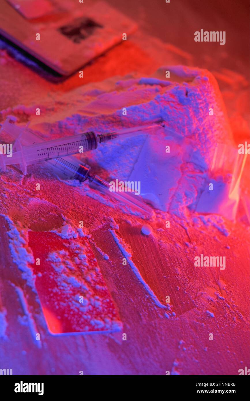 Droga, casa del commerciante della droga. Cocaina confezionata in bustine, scaglie: Compresse e siringhe al neon. Non valido, immissione. Foto Stock