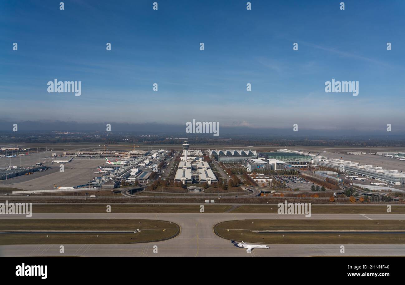 Vista aerea della torre di controllo del traffico aereo, edifici terminali principali, taxi e grembiule con diversi tipi di aerei di diverse compagnie aeree presso l'aeroporto di Monaco 'Frank Josef Strauss' Foto Stock