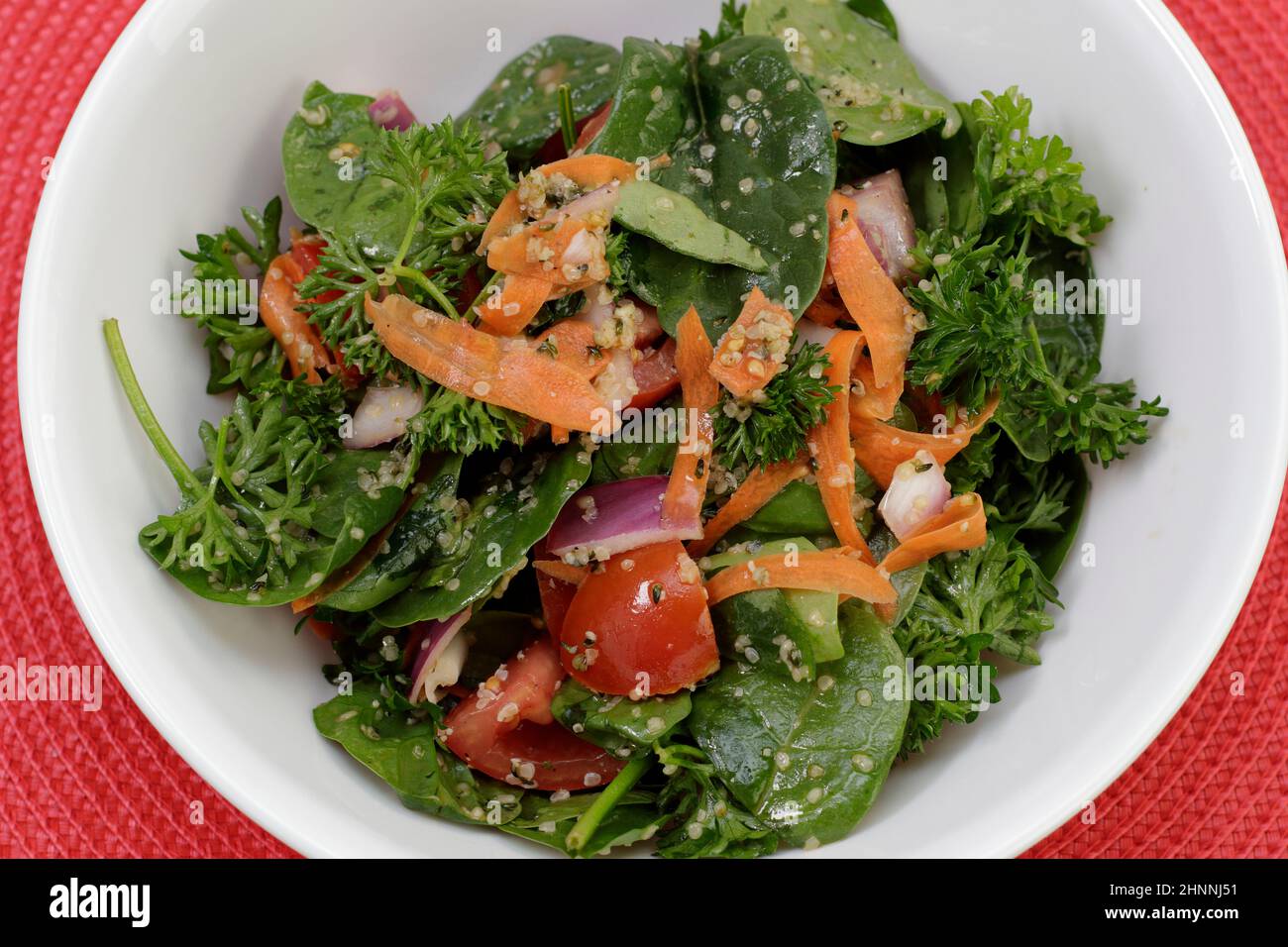 Verdure nutritive di spinaci e insalata di prezzemolo con verdure miste, cuori di canapa sgusciati e condimenti. Ciotola di un'insalata densa nutriente molto nutriente Foto Stock