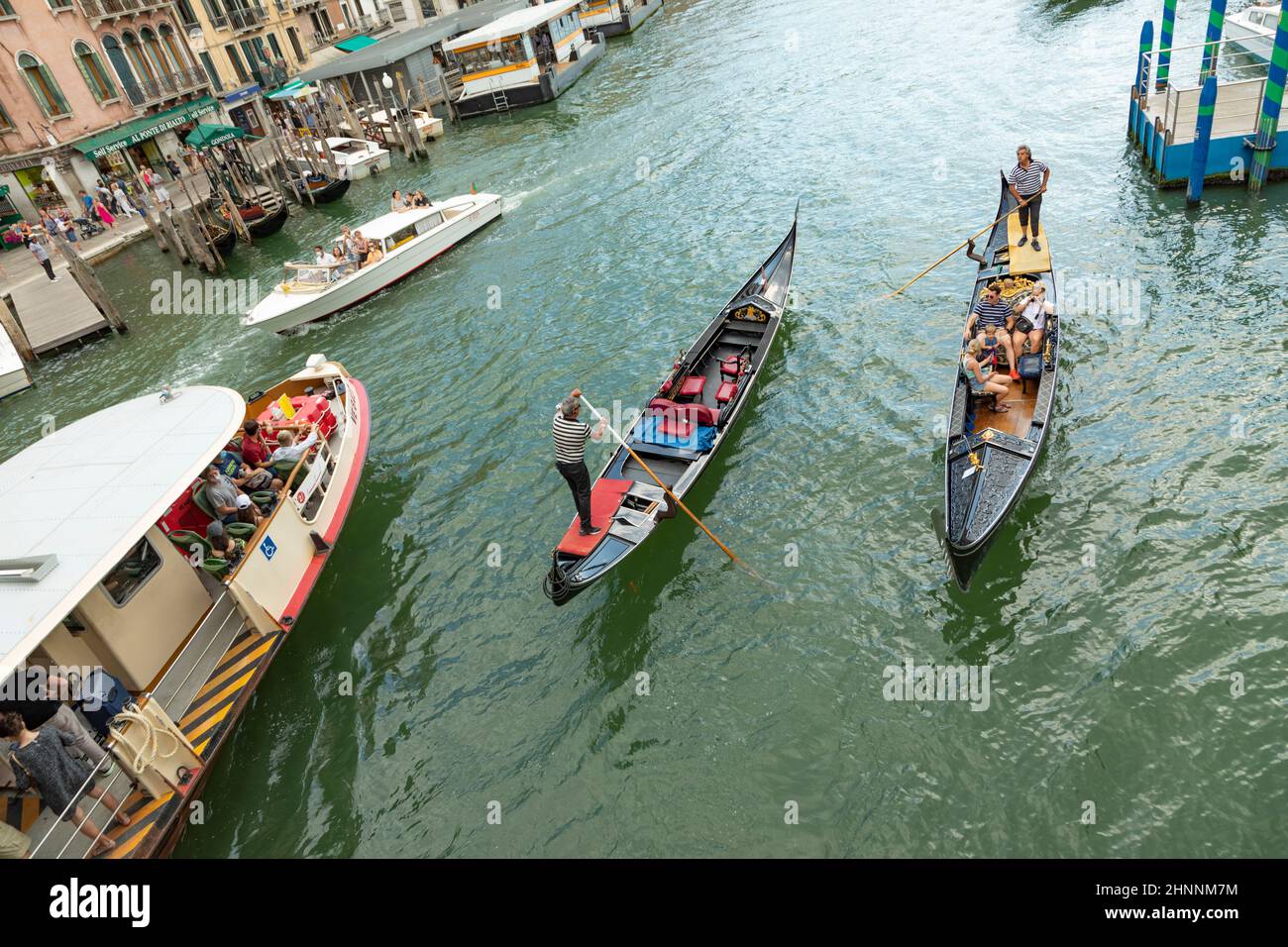 Diverse imbarcazioni da trasporto come Taxi, vaporetto e gondola con turisti al canale Grande di Venezia Foto Stock