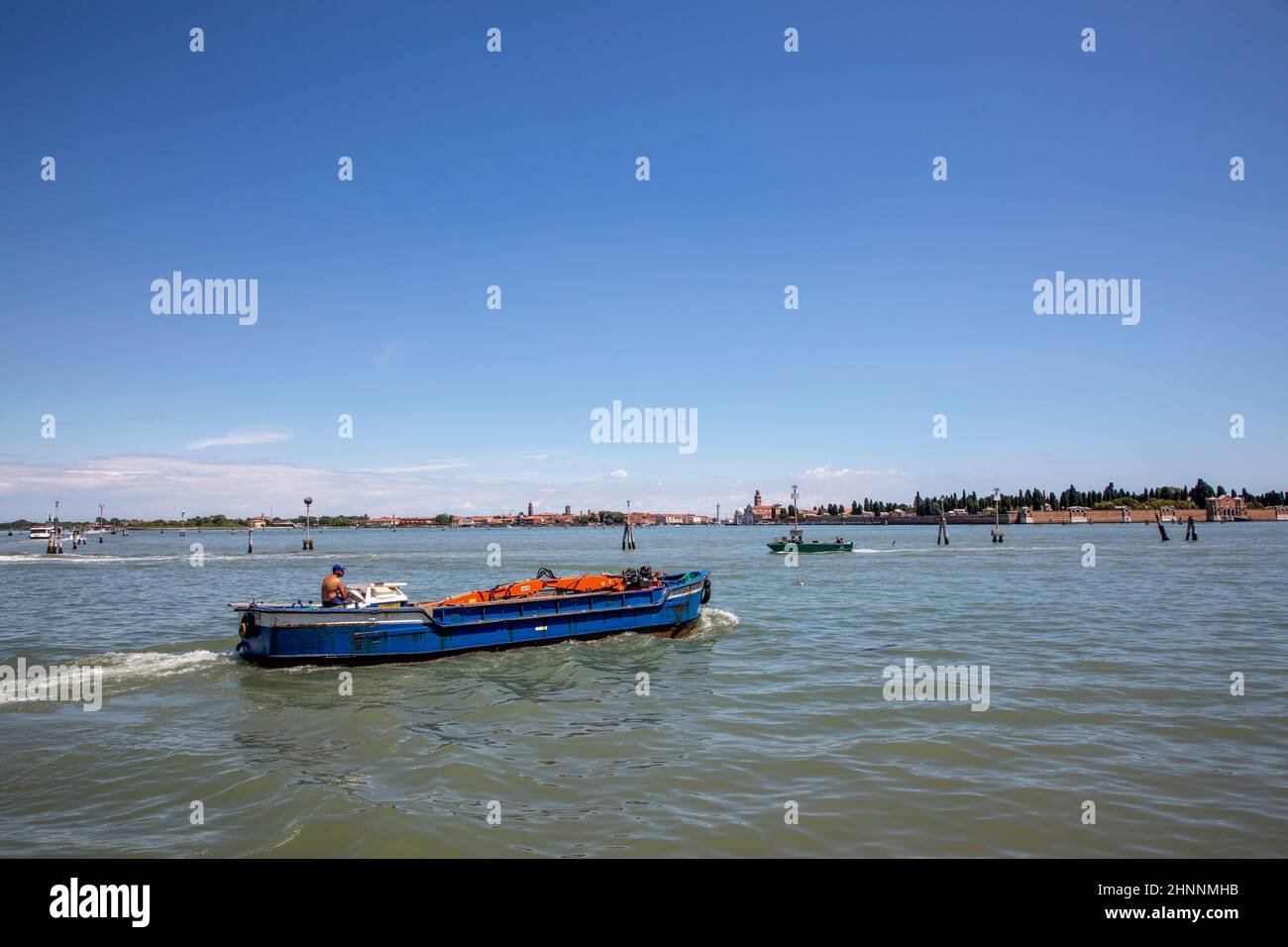 L'operaio con la sua gru guida con la sua nave al cantiere che passa la laguna di Venezia Foto Stock
