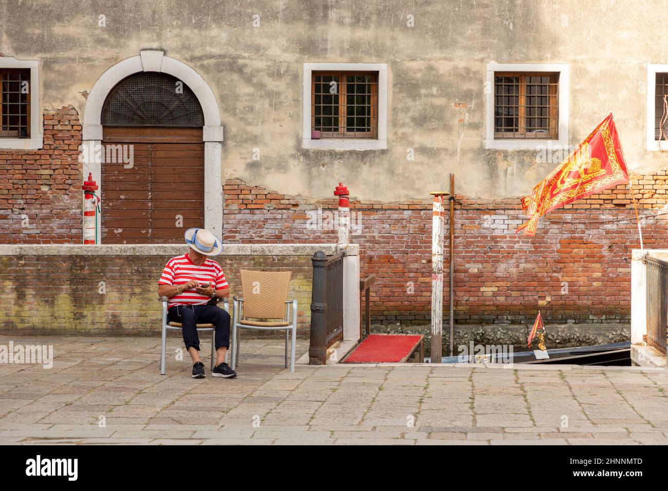 gondoliere si siede su una sedia e aspetta i turisti. A causa della pandemia di Corona ci sono solo alcuni turisti a Venezia, Italia Foto Stock