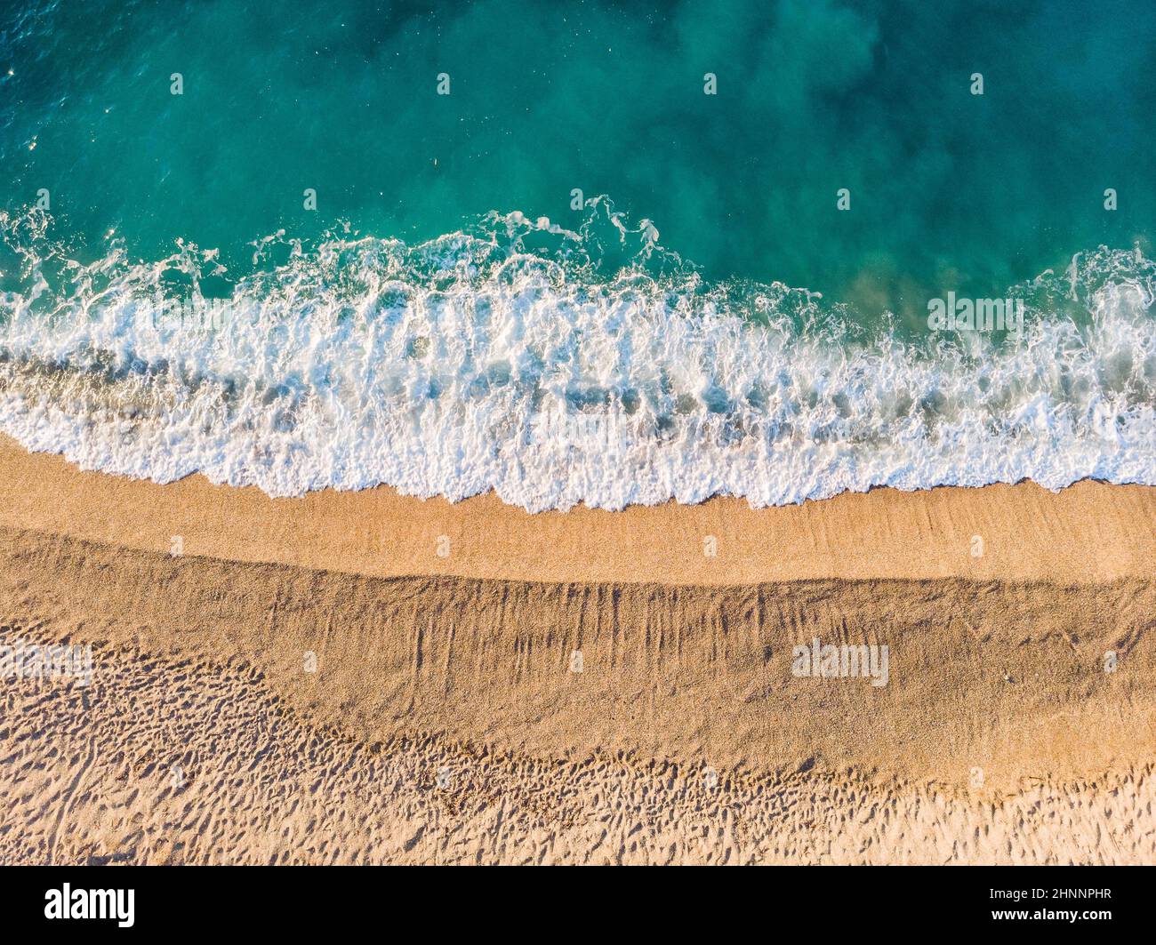 Vista aerea dall'alto in basso di una spiaggia di sabbia pulita sulle rive di un bel mare turchese ligure, Italia Foto Stock