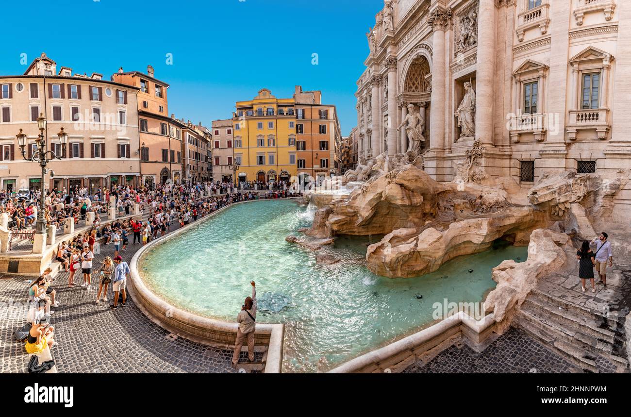 La gente visita la fontana di Trevi a Roma. Gettare le monete nella fontana dovrebbe dare fortuna alla gente. Foto Stock