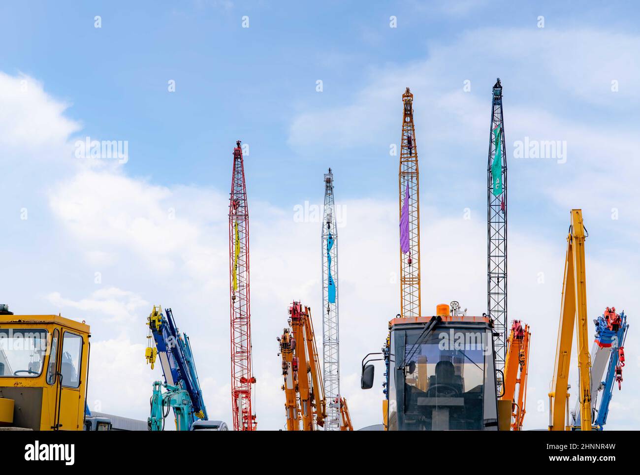 Gru mobile close-up, apripista giallo e retroescavatore blu parcheggiati in un cantiere d'asta di macchinari di seconda mano contro il cielo blu. Macchinari pesanti in affitto e vendita. Concessionaria gru per edilizia. Foto Stock