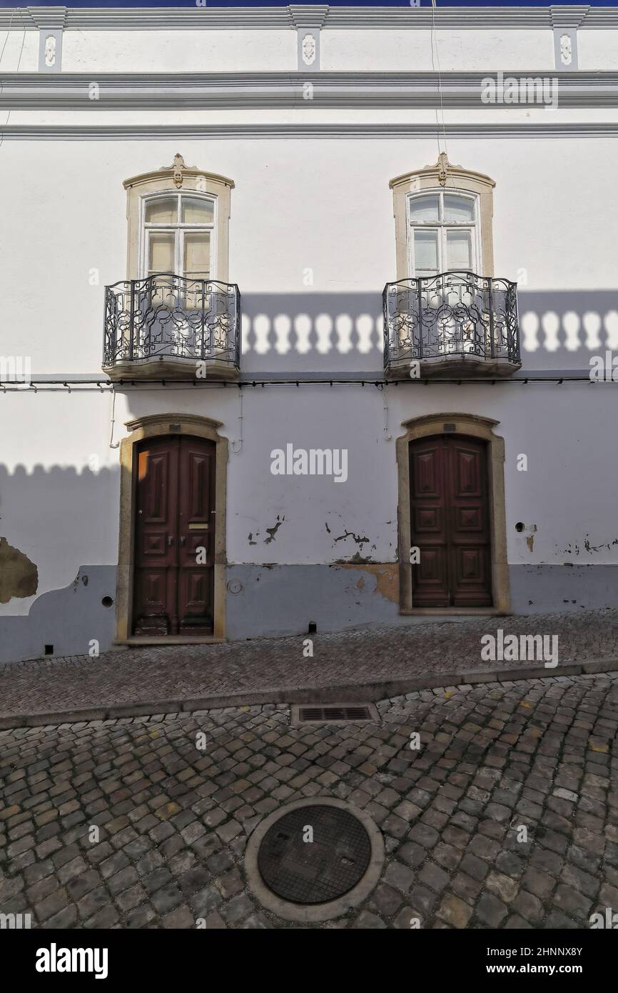Facciata dipinta di bianco con linee d'ombra della casa cittadina neoclassica, ringhiera in metallo, balconi, porte in legno. Tavira-Portogallo-118 Foto Stock