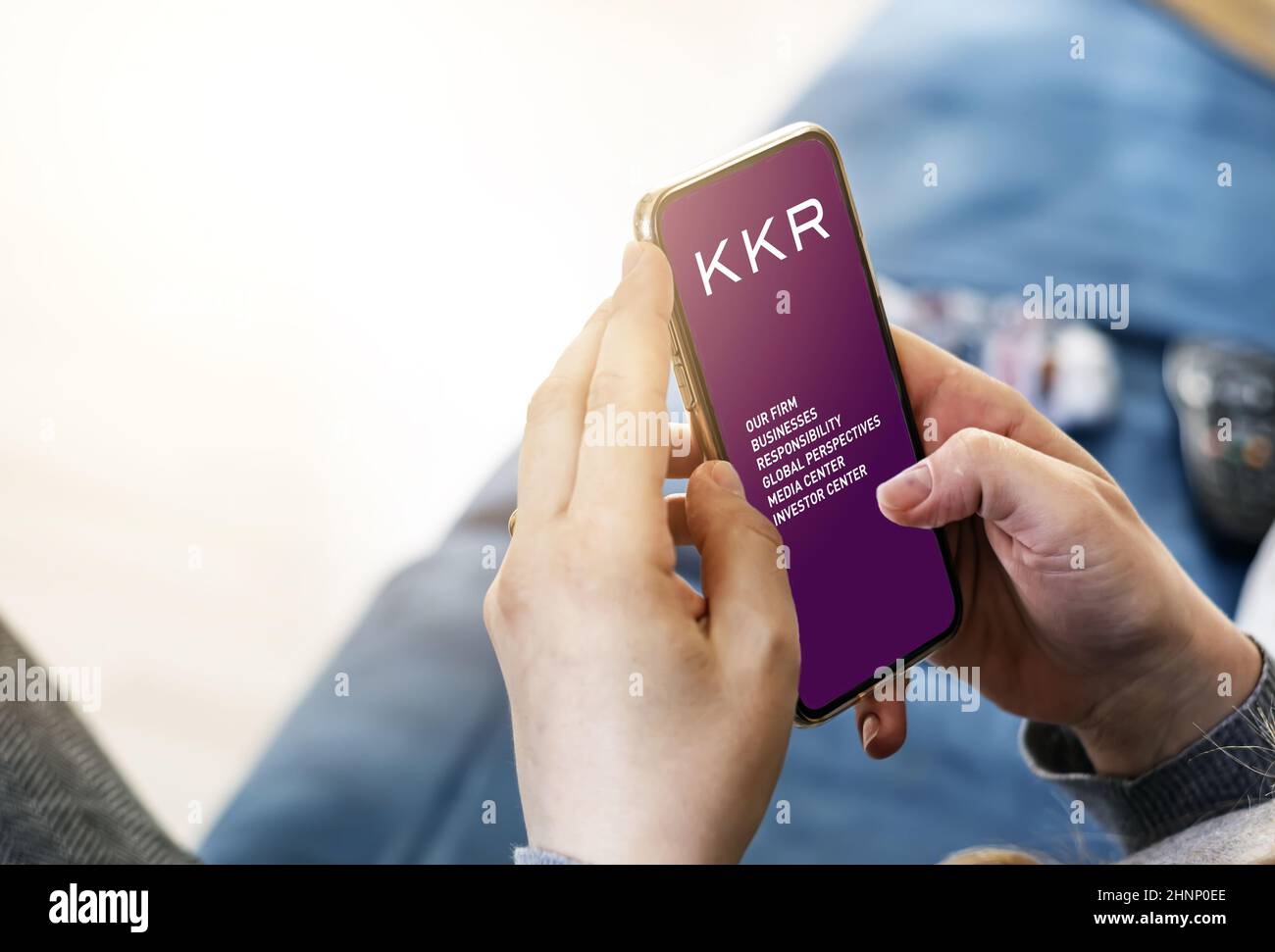 Giovane donna che usa il suo cellulare con l'applicazione della società di investimento americana KKR Foto Stock