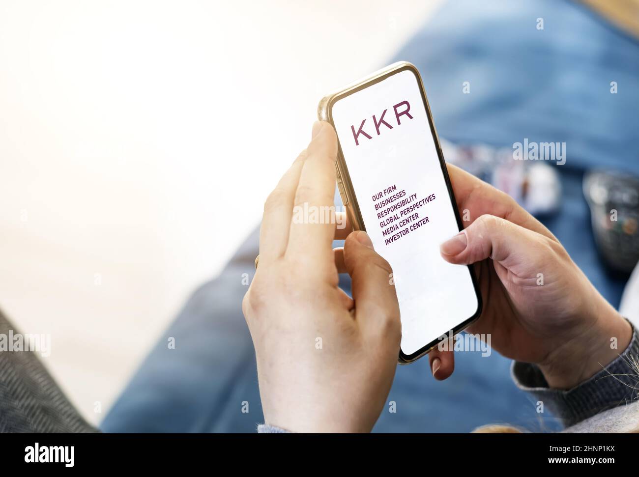 Giovane donna che usa il suo cellulare con l'applicazione della società di investimento americana KKR Foto Stock