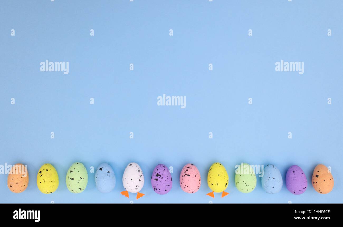 Concetto creativo di Pasqua con uova colorate su sfondo blu pastello. Disposizione piatta spazio minimo per la copia Foto Stock