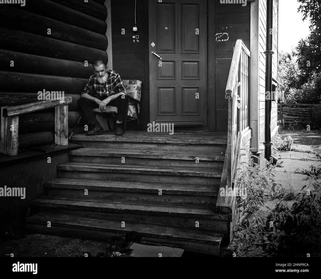 19th del 2018 luglio, Russia, Tomsk, uomo più anziano siede al portico di casa di legno Foto Stock