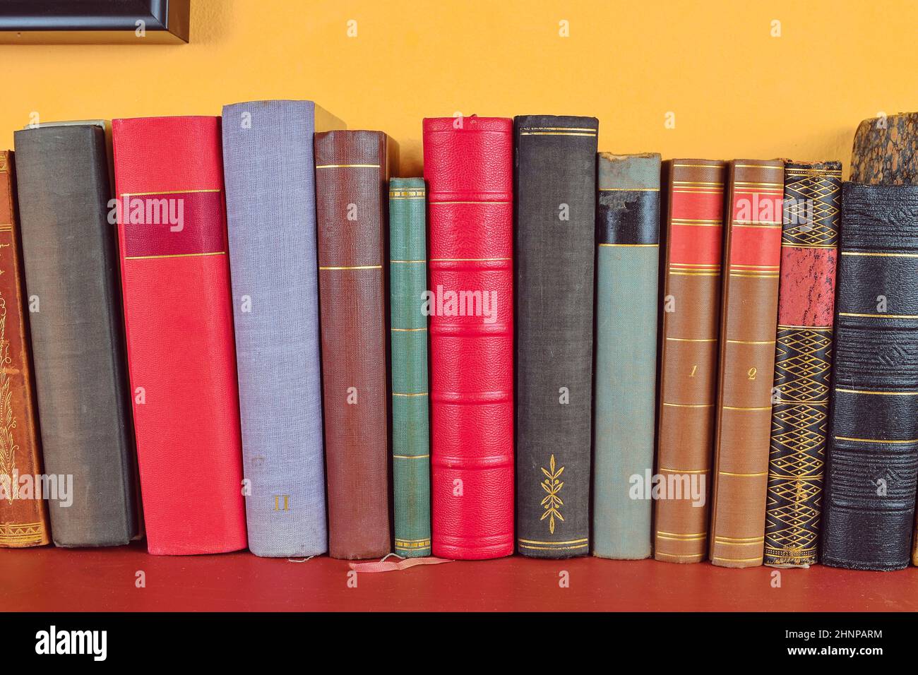 Ripiano in legno con la sua storica,decorate, vintage libri. Libri antichi su giallo e claret sfondo Foto Stock