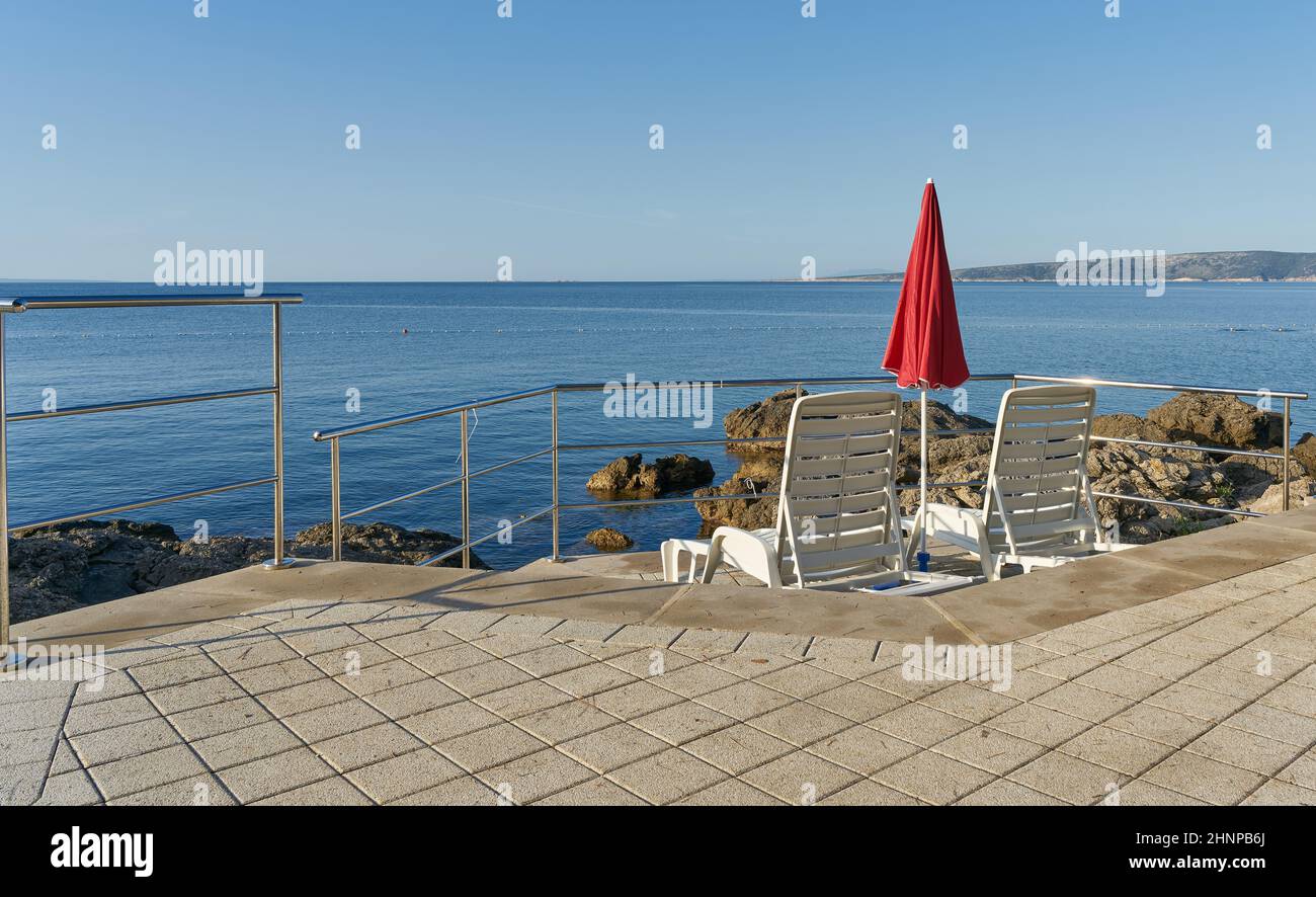 Ombrellone e lettini sulla costa adriatica vicino alla città di Krk in Croazia Foto Stock