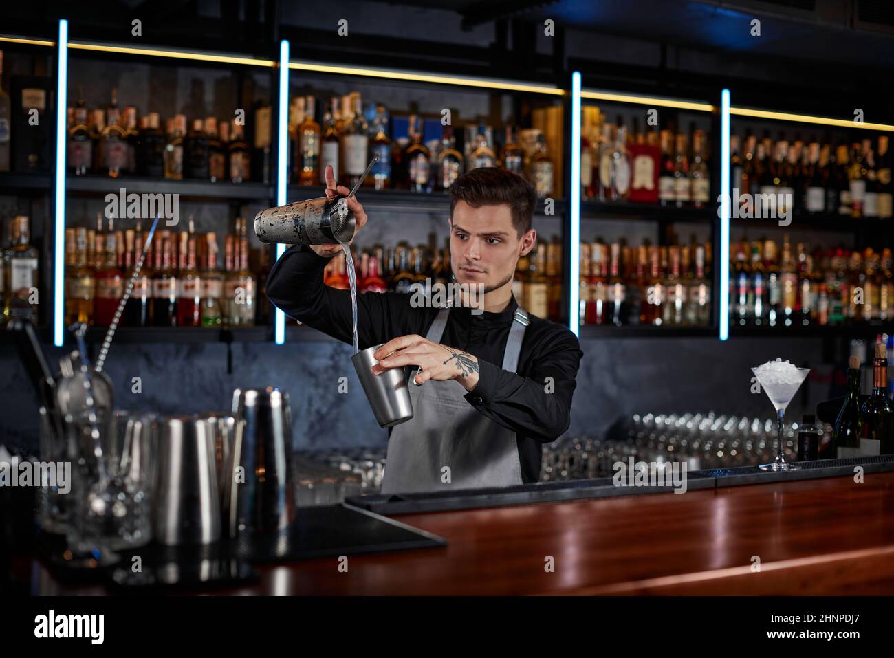 il barman sta facendo il cocktail con lo shaker dell'acciaio Foto Stock