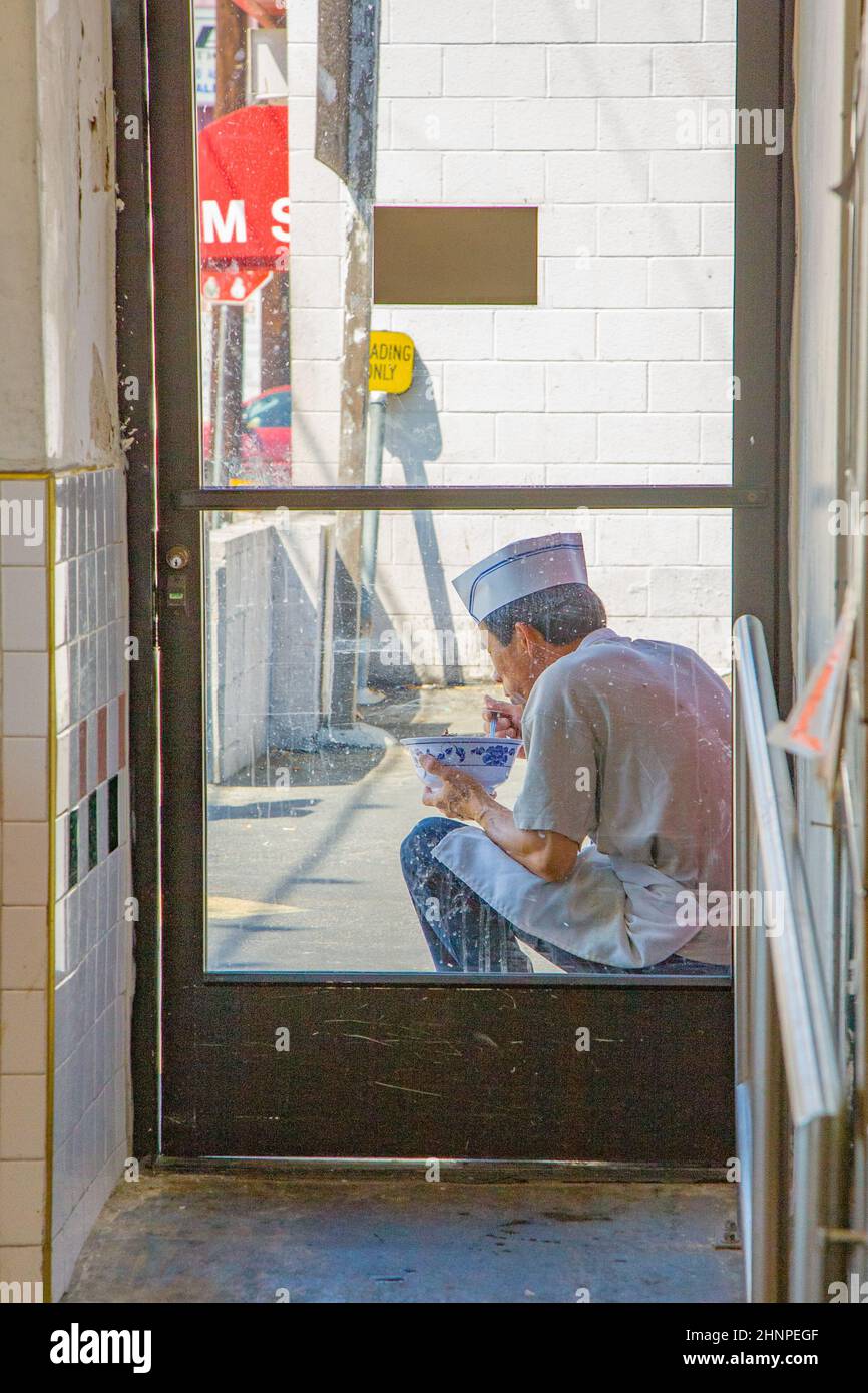 il cuoco cinese a chinatown gode il suo pranzo nel cortile del ristorante Foto Stock