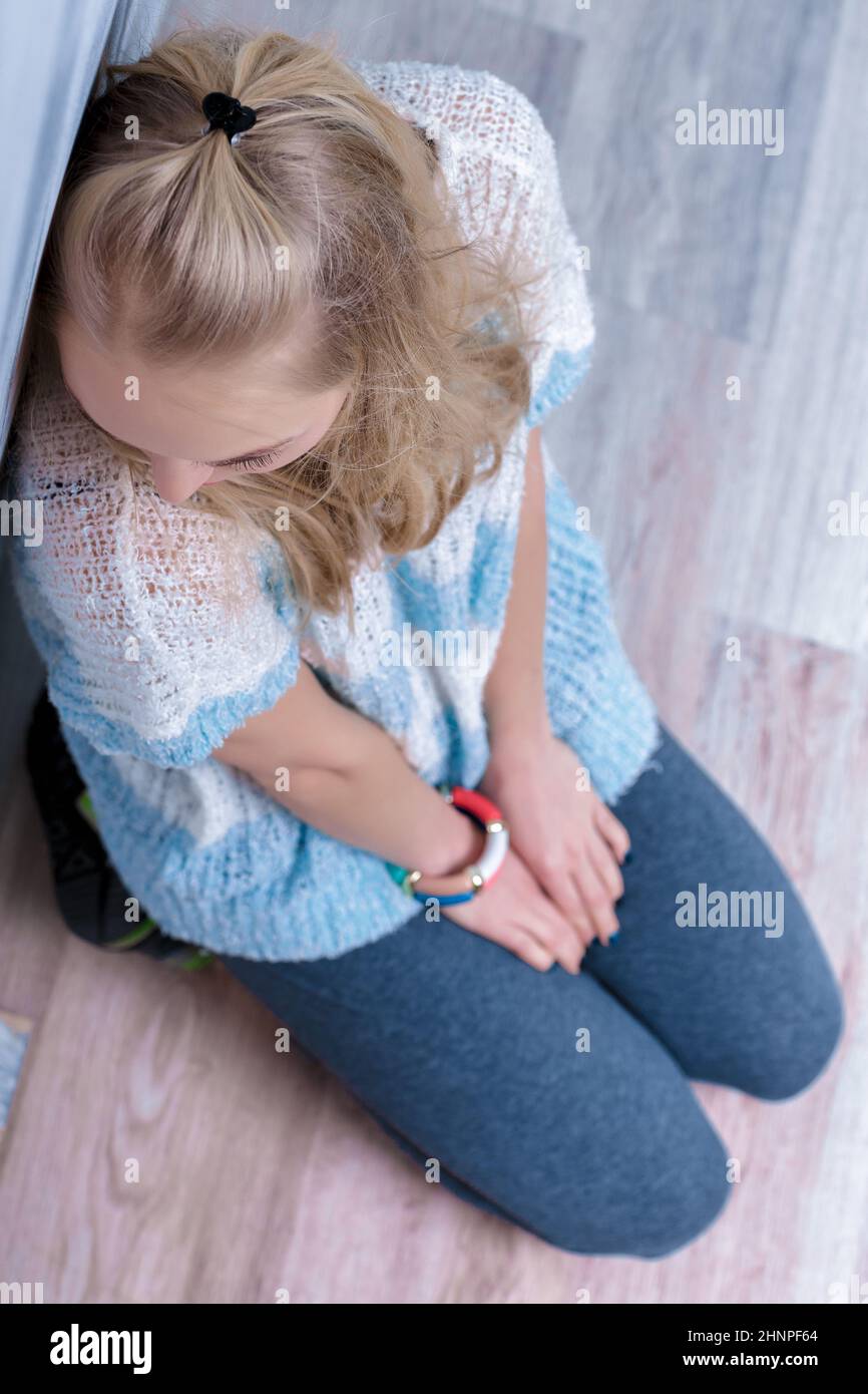 depressione donna bionda seduta sul pavimento. vista dall'alto Foto Stock