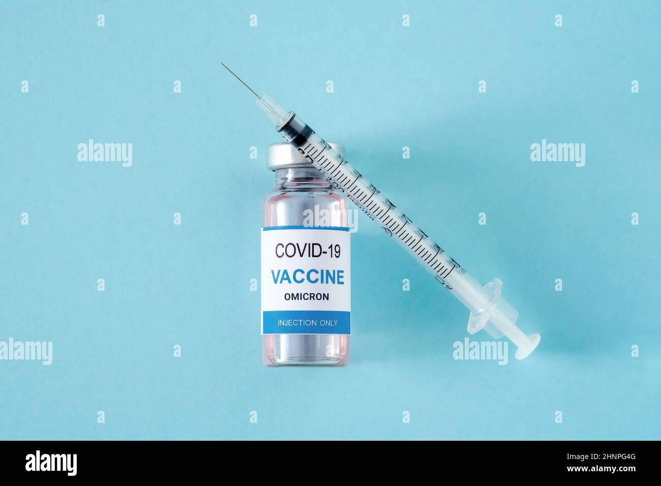Flaconcino con vaccino per coronavirus Omicron variante e siringa su sfondo blu Foto Stock