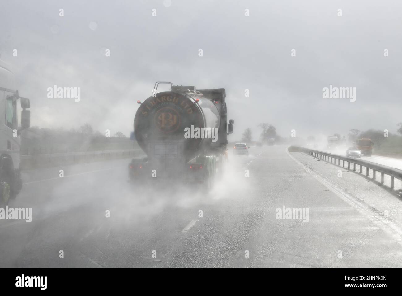 Guida in autostrada con scarsa visibilità con pioggia e spruzzi stradali provenienti dai veicoli che precedono la guida al sole - Regno Unito Foto Stock