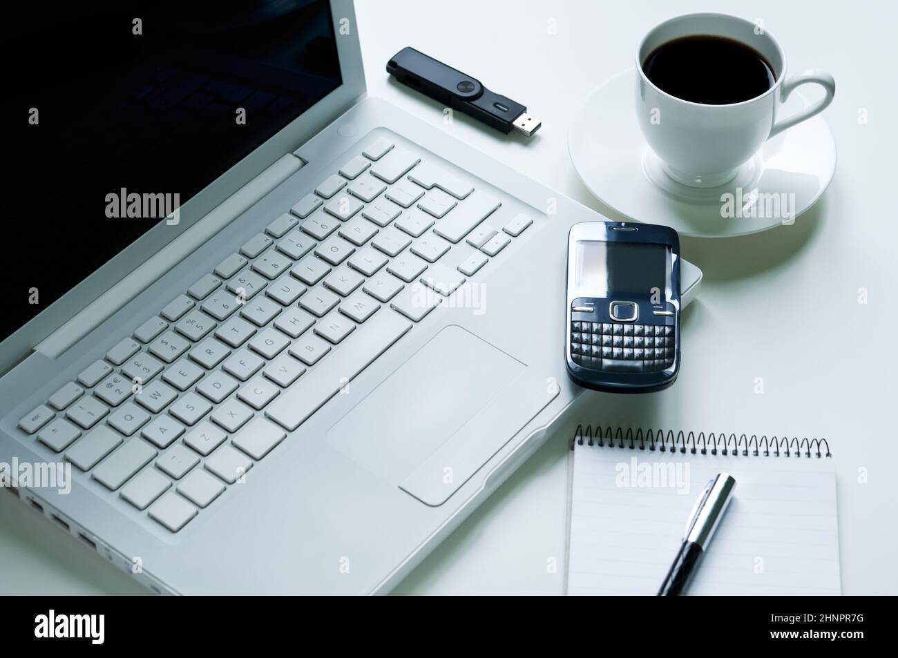 Laptop moderno con telefono cellulare, una tazza di caffè, il blocco note e penna stilografica e pendrive usb Foto Stock