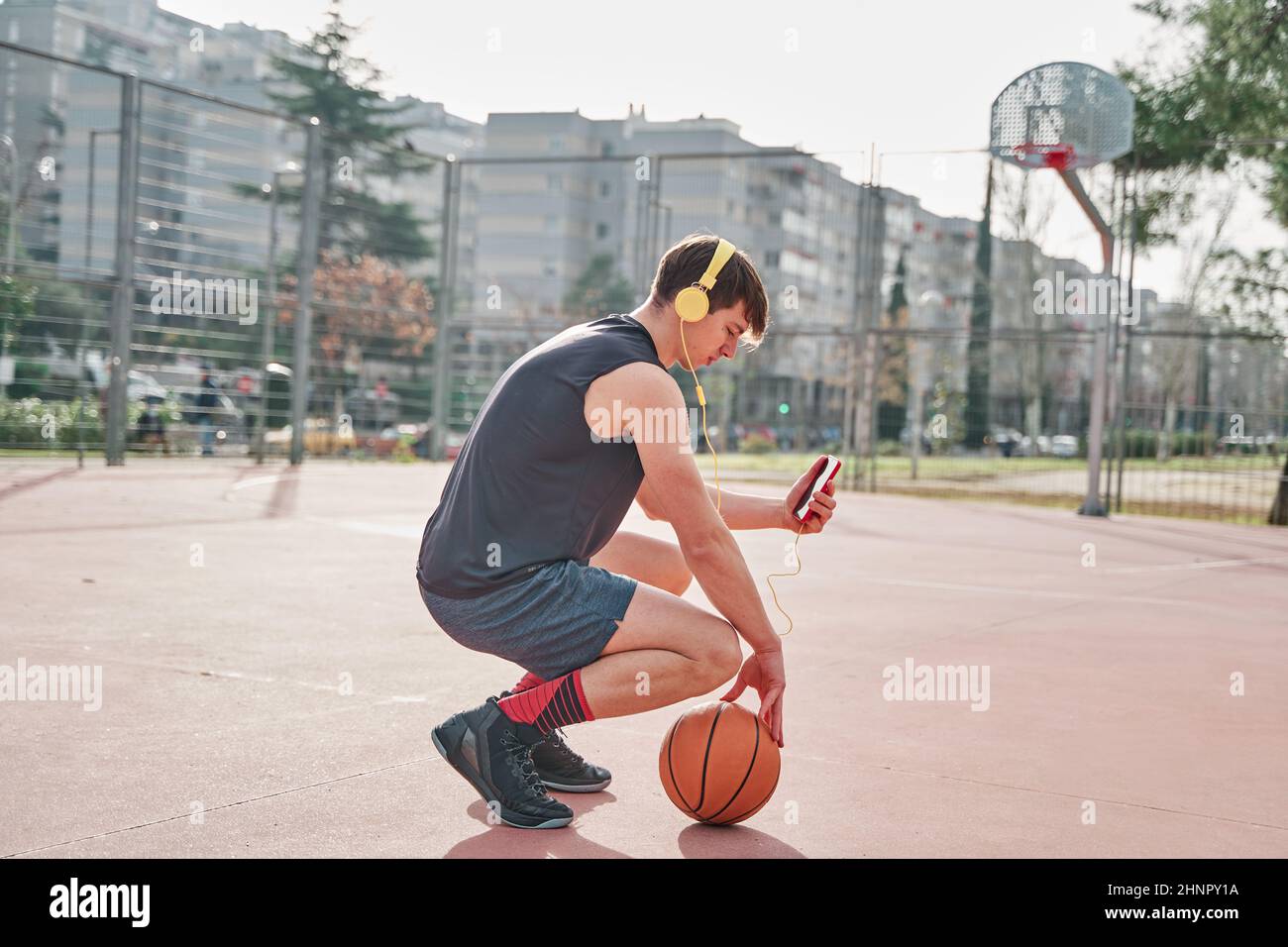giovane atleta che si allena in campo di pallacanestro mentre ascolta la musica. Foto Stock