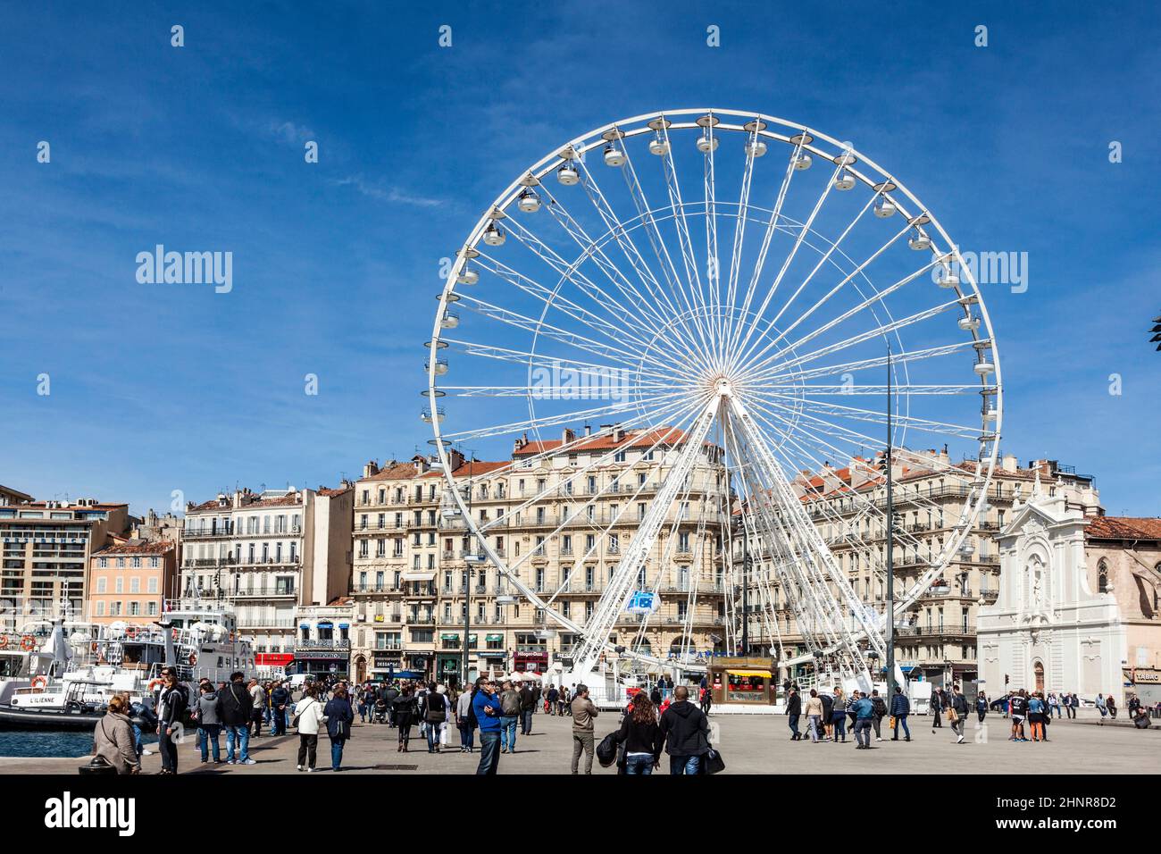 La gente gode di una grande ruota di ferro contro un cielo blu a Marsiglia Foto Stock