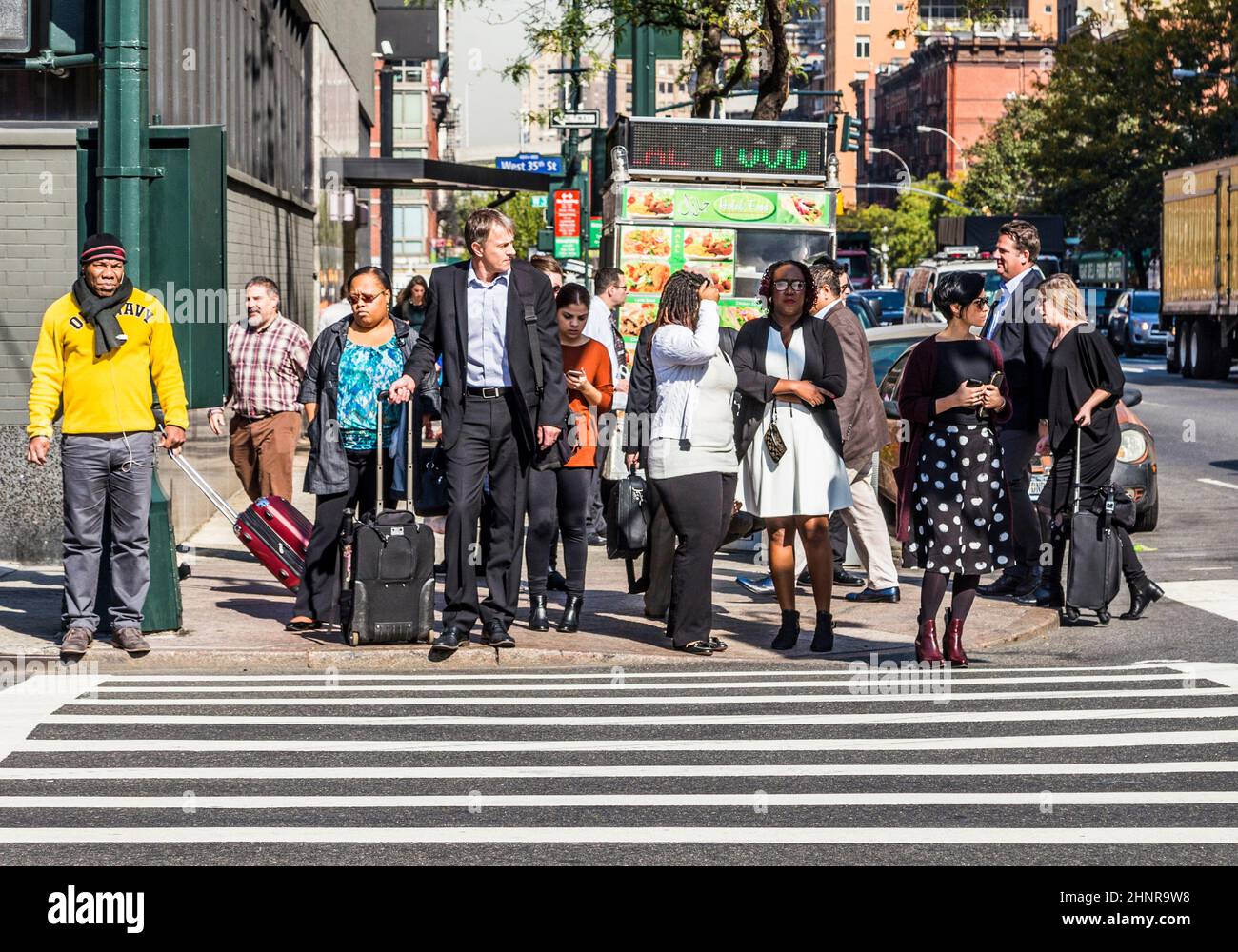 La gente vicino a Wall Street a Manhattan attraversa la strada al semaforo bianco Foto Stock