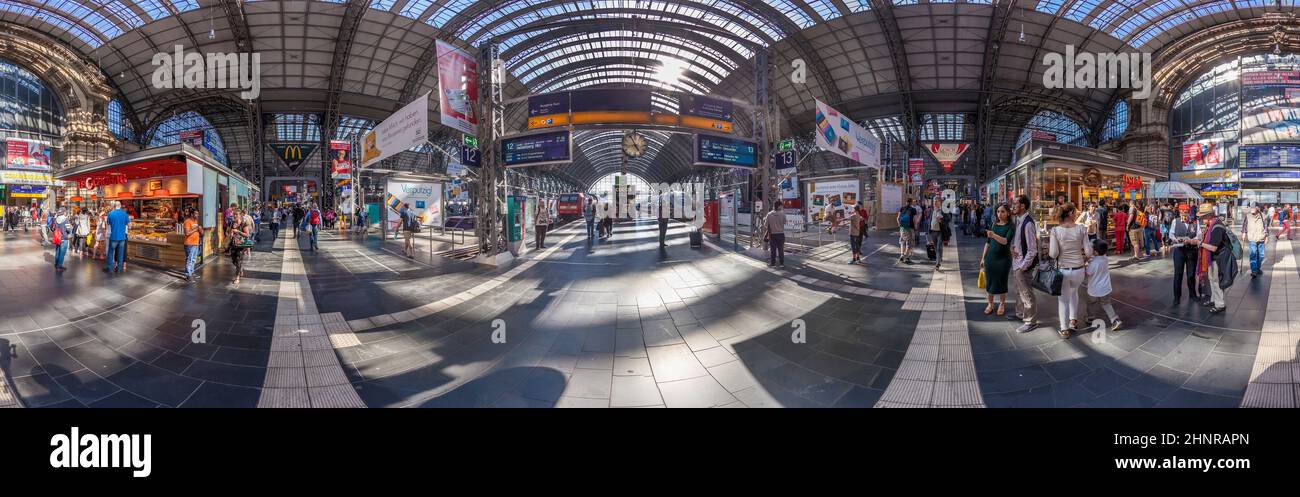 I viaggiatori camminano tra i chioschi e le porte di partenza alla stazione ferroviaria di Francoforte Foto Stock