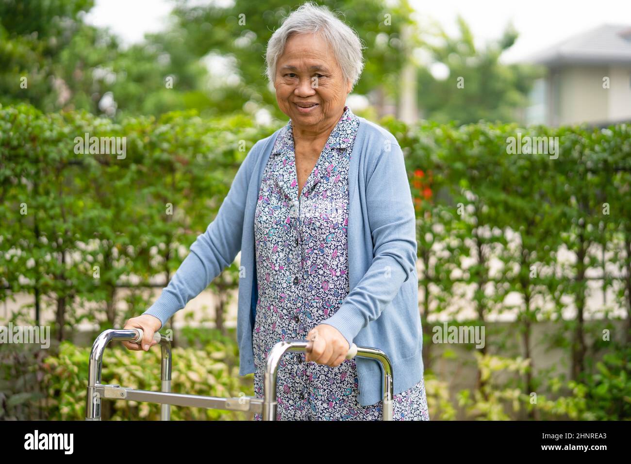 Anziano asiatico o anziana donna anziana uso walker con salute forte mentre camminando al parco in vacanza felice Foto Stock