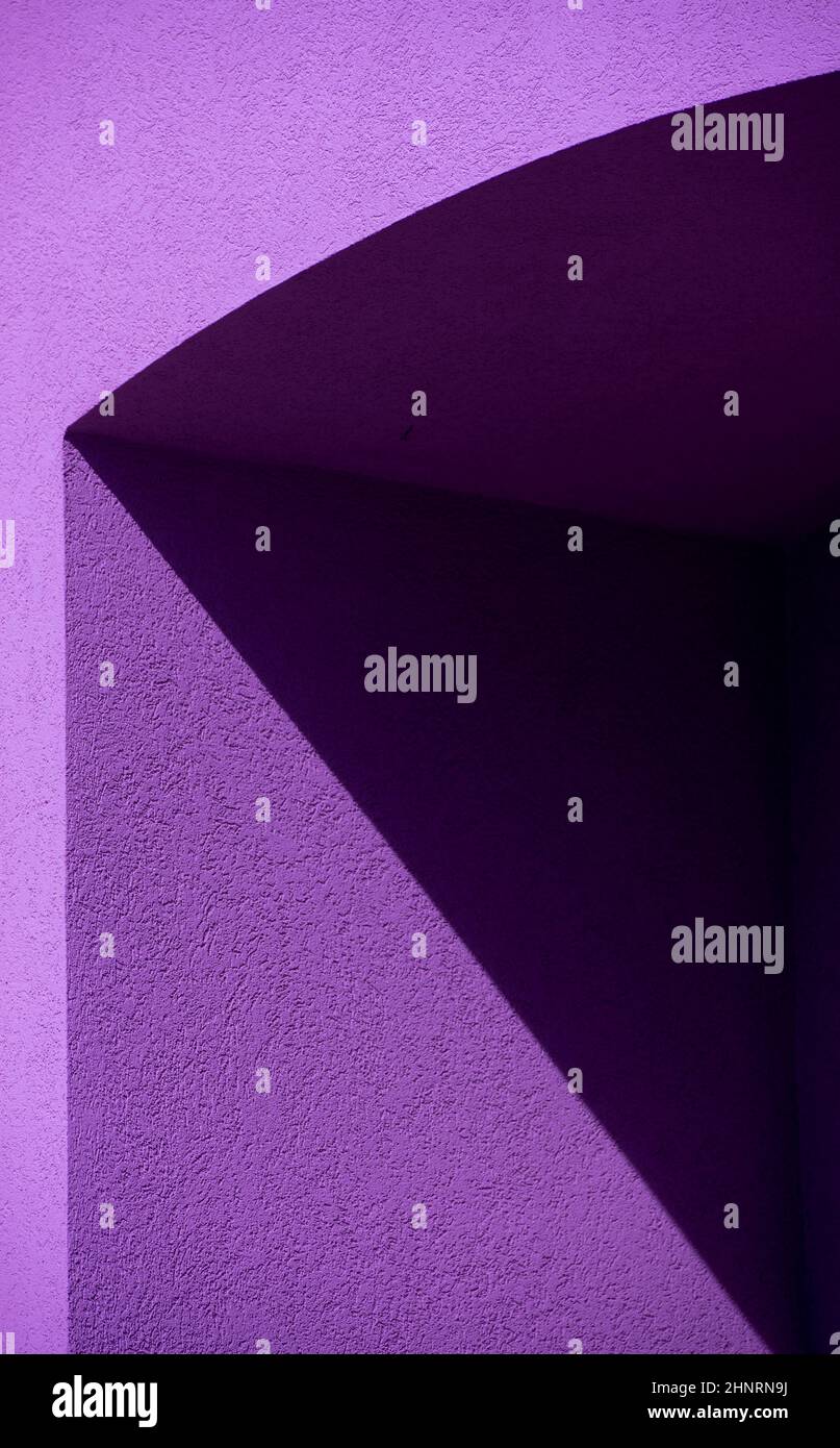 forme geometriche di ombra nera e viola su pareti esterne in cemento o cemento dell'edificio in luce pomeridiana che dividono le linee nere che separano l'immagine Foto Stock