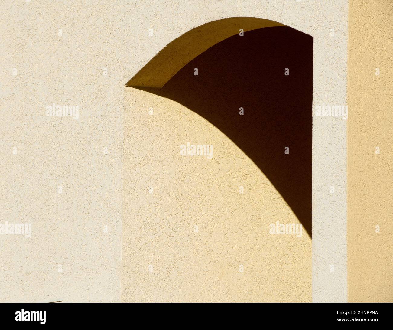 astratto disegno ombra su cemento giallo cemento parete di forme geometriche arco di edificio esterno linee curve triangolari e angoli contrasto Foto Stock