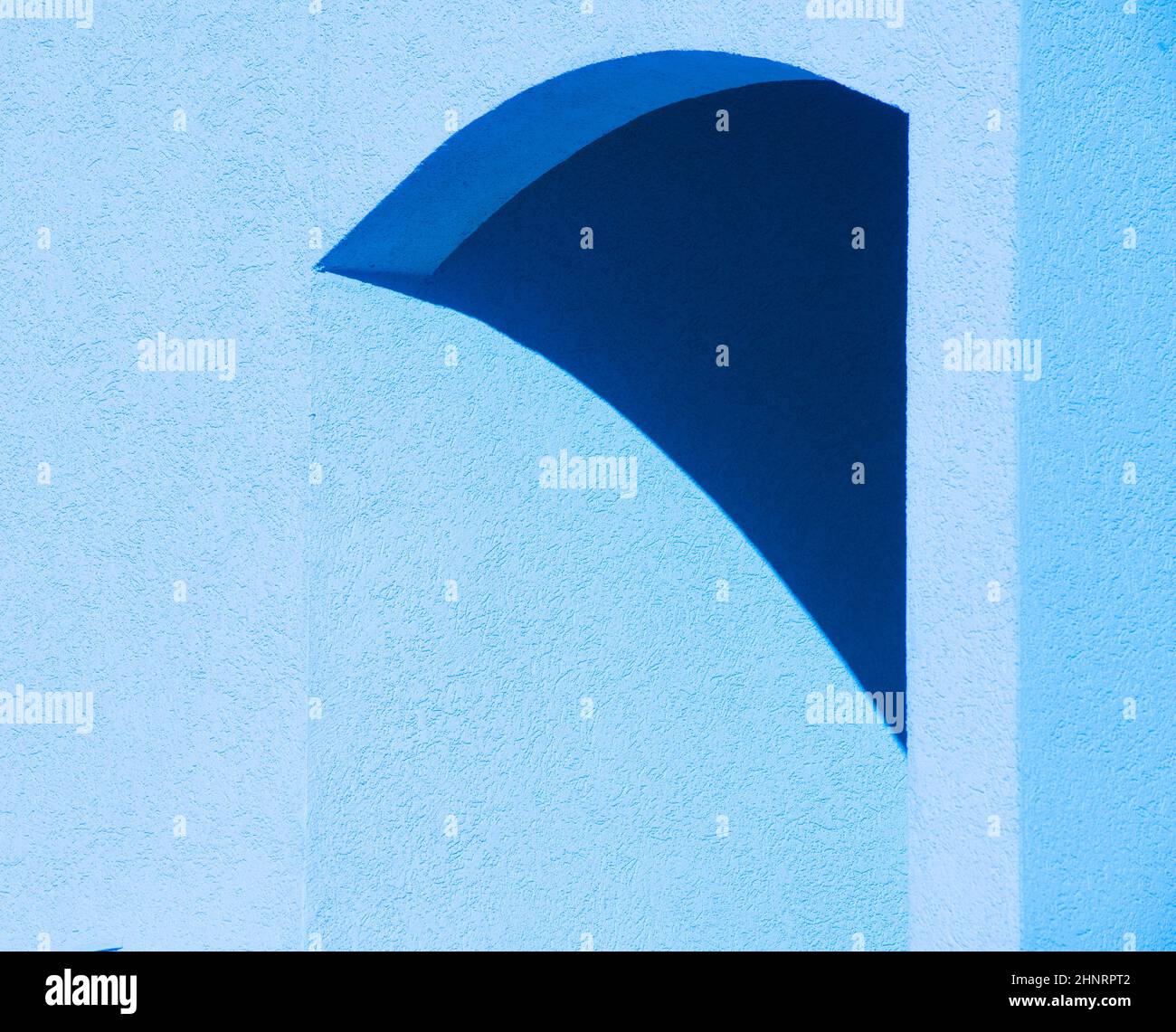 disegno astratto di ombra su parete di cemento di cemento blu che crea forme gemoetrical in arco di costruzione esterna linee curve triangolari e angoli Foto Stock