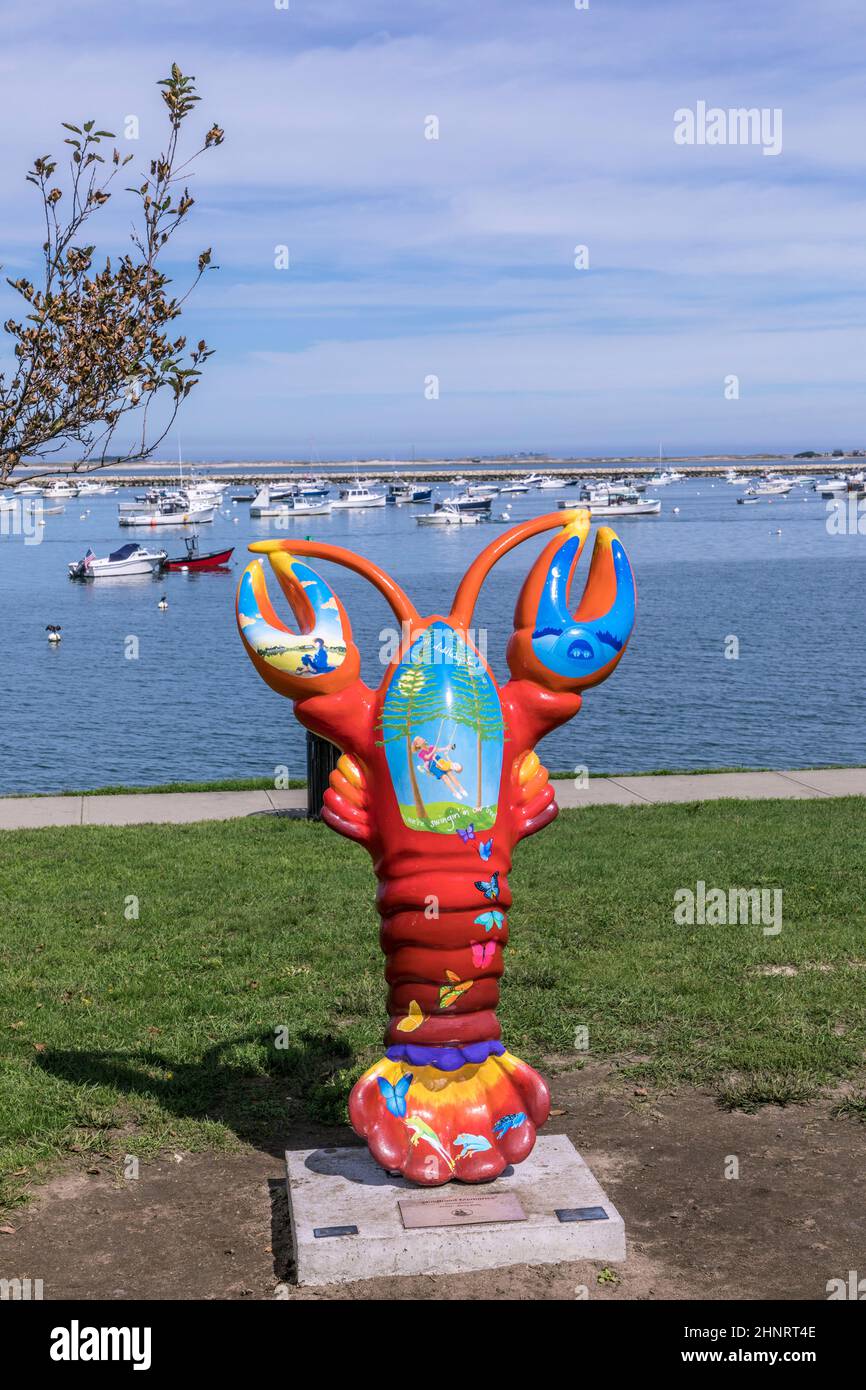 Scultura colorata di aragosta dipinta da artisti locali sul lungomare di Plymouth con il porto e le navi sullo sfondo Foto Stock