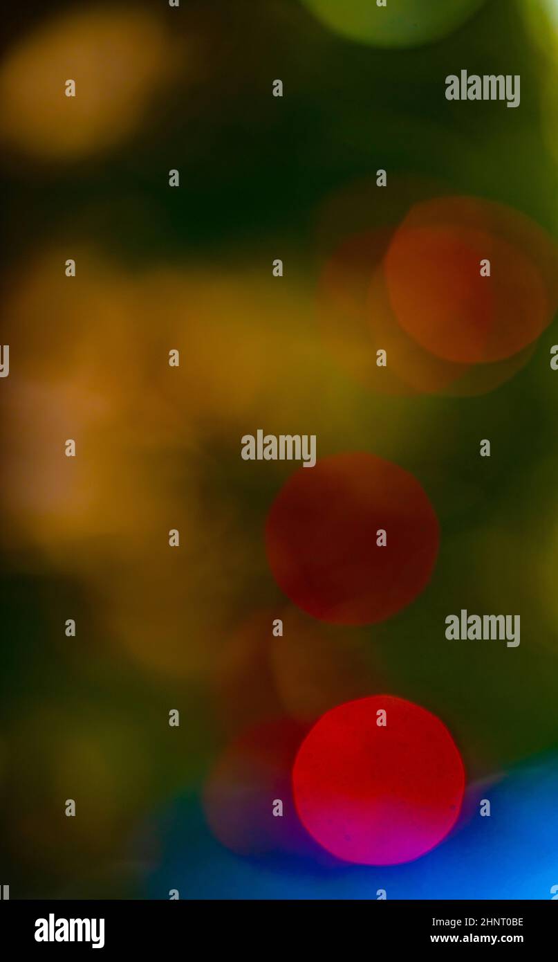 Bokeh effetti speciali fuoco morbido di Natale luci colorate in esterno albero inverno verde rosso giallo e bianco bokeh cerchi palline colorate verticali Foto Stock