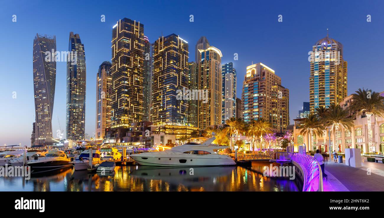 Dubai Marina e il porto skyline architettura ricchezza viaggi di lusso con barca a vela al panorama notturno negli Emirati Arabi Uniti Foto Stock