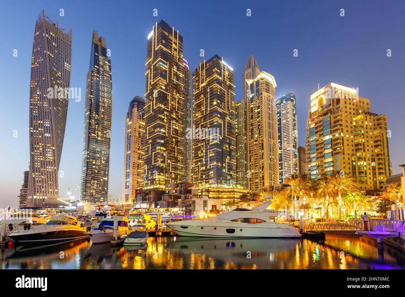 Dubai Marina e il porto skyline architettura ricchezza viaggi di lusso con barca a vela di notte negli Emirati Arabi Uniti Foto Stock
