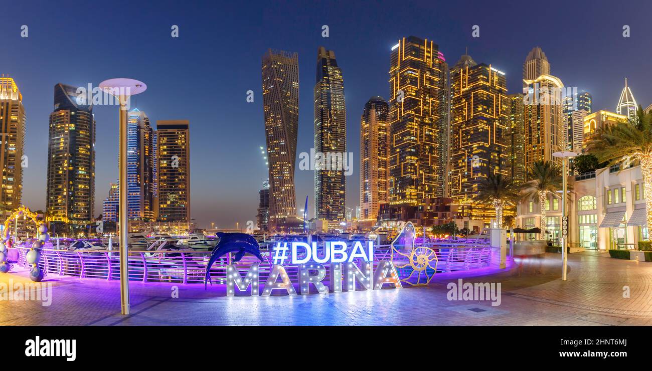 Il logo Dubai Marina e l'architettura dello skyline del porto ricchezza di viaggi di lusso di notte negli Emirati Arabi Uniti Foto Stock
