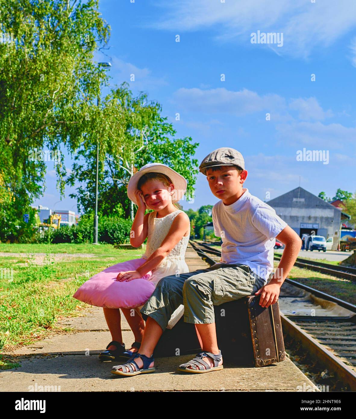 Adorabile bambina e ragazzo su una stazione ferroviaria, attesa per il treno con valigie vintage. Viaggi, vacanze e piccoli concetto. Assicurazione di viaggio concetto. Viaggio di vacanza Foto Stock