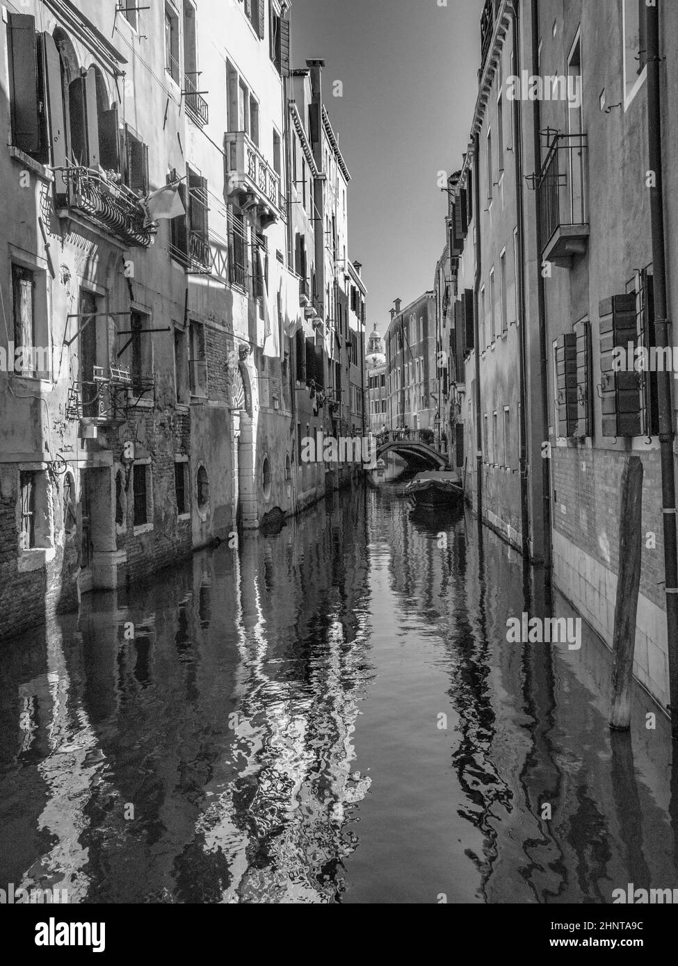 piccolo canale nella città di venezia con case strette in bianco e nero Foto Stock