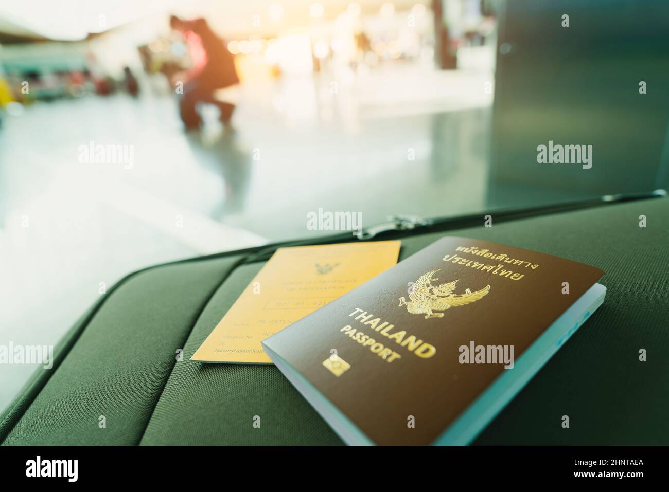 Thailandia passaporto e vaccino passaporto sul bagaglio su sfondo sfocato del turista in aeroporto. Certificato di vaccinazione per viaggi durante il focolaio di coronavirus. Le parole thailandesi sono il passaporto thailandese. Foto Stock