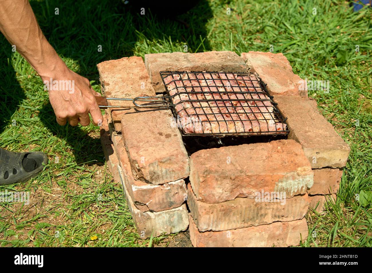 Shish kebab è fritto su una griglia su carboni e mattoni Foto Stock