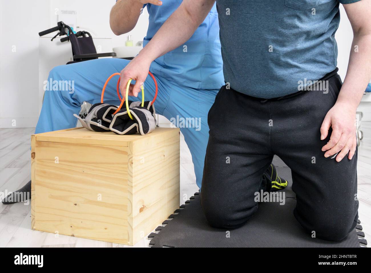 Uomo con disabilità fare esercizio di recupero con dumbbell. Uomo con Ataxy in terapia di supporto di recupero fisioterapia sistema sanitario. Foto Stock