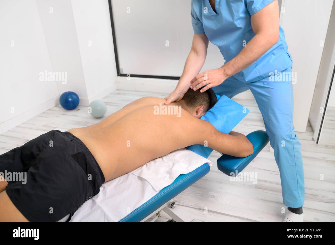 Fisioterapista massaggiando la schiena di un giovane atleta nella clinica di riabilitazione sportiva. Foto Stock